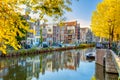 Autumn morning in Amsterdam. Silence. Ancient houses are reflected in the water of the canal, the sun shines through the trees. Royalty Free Stock Photo