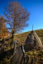 Autumn mountain landscape with stacks and wooden fence. Beautiful sunny autumn mountain view with hay stacks, rustic fence, sunny Royalty Free Stock Photo