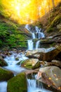 Autumn mountain waterfall stream in the rocks with colorful fallen dry leaves, landscape