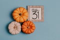 Autumn October flat lay. Orange mini pumpkins and calendar date in wooden frame. Halloween day. Blue background. Oak leaves. Fall