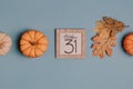 Autumn October flat lay. Orange mini pumpkins and calendar date in wooden frame. Halloween day. Blue background. Oak leaves. Fall