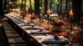 Autumn outdoor long banquet table setting in the woods with candles and flowers Royalty Free Stock Photo