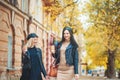 Autumn outdoor! Outdoors shot of young women with coffee on city street. Two fashion girls walking outdoor with cofee. Royalty Free Stock Photo