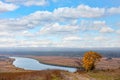 View of a wooden bench on a high river bank on a bright autumn day. Rural autumn landscape Royalty Free Stock Photo