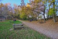 Autumn park full of visiters, wooden tables and chairs on a sunny day. Family weekend in park Royalty Free Stock Photo