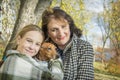 In the autumn park, a mother with her daughter holds a dachshund in her arms