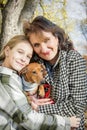 In the autumn park, a mother with her daughter holds a dachshund in her arms