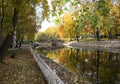 Autumn Park, trees reflected in the pond white rusty fence, withered leaves, stone waterfall Royalty Free Stock Photo