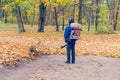 In the autumn park worker removes the road from the fallen leaves with help