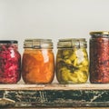 Autumn pickled colorful vegetables in jars placed in row Royalty Free Stock Photo