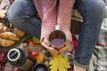 Autumn picnic in the park, warm autumn day. The girl holds a cup with tea in her hands. Basket with flowers on a blanket in yellow