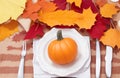 Autumn place setting with fall leaves, napkin and pumpkins. Thanksgiving autumn place setting with cutlery and arrangement of fall