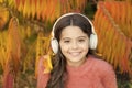 Autumn playlist concept. Feel joy. Kid girl relaxing near autumn tree with headphones. Music for autumn cozy mood