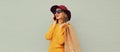 Autumn portrait of beautiful happy smiling young woman with shopping bag calling on mobile phone looking away wearing hat, yellow Royalty Free Stock Photo