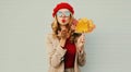 Autumn portrait of beautiful woman with yellow maple leaves, female model blowing red lips sending sweet air kiss Royalty Free Stock Photo