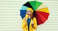 Autumn portrait beautiful young woman with colorful umbrella and cup of juice wearing a yellow coat and beret on a white Royalty Free Stock Photo