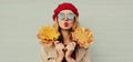 Autumn portrait beautiful young woman model with yellow maple leaves blowing her lips with lipstick wearing a red french beret Royalty Free Stock Photo