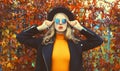 Autumn portrait of beautiful young woman wearing black round hat, sunglasses and coat jacket in the park on leaves background Royalty Free Stock Photo