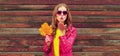 Autumn portrait of beautiful young woman with yellow maple leaves blowing her lips with lipstick wearing red heart shaped Royalty Free Stock Photo