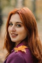 Autumn portrait of candid beautiful red-haired girl with fall leaves in hair. Royalty Free Stock Photo