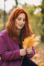 Autumn portrait of candid beautiful red-haired girl with fall leaves in hair. Royalty Free Stock Photo