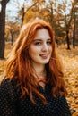 Autumn portrait of candid beautiful red-haired girl with fall leaves in hair. Royalty Free Stock Photo