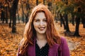 Autumn portrait of candid beautiful red-haired girl with fall leaves in hair. Royalty Free Stock Photo