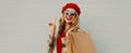 Autumn portrait cheerful happy smiling woman with shopping bags wearing a red french beret on gray background Royalty Free Stock Photo