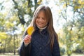 Autumn portrait of cute little blond girl in city park. Beautiful laughing child holding a yellow leaf, having fun Royalty Free Stock Photo