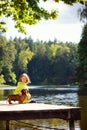 Autumn portrait of a girl child with a dog red Dachshund on the bridge in Sunny Park. Friends sit on the bridge by the water Royalty Free Stock Photo