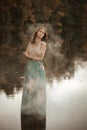 Autumn portrait of a girl standing in a forest lake. Royalty Free Stock Photo