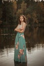 A girl is dancing on a wooden bridge against the backdrop of a forest lake. Royalty Free Stock Photo