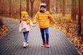 Autumn portrait of happy brother and sister walking the road in sunny park Royalty Free Stock Photo