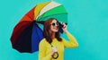 Autumn portrait happy cheerful smiling young woman photographer with colorful umbrella and camera taking a picture on blue Royalty Free Stock Photo