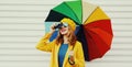 Autumn portrait happy cheerful smiling young woman photographer with colorful umbrella and camera wearing a yellow coat and Royalty Free Stock Photo