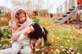 Autumn portrait of happy kid girl playing with her spaniel dog in the garden Royalty Free Stock Photo