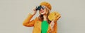 Autumn portrait happy smiling young woman with film camera and yellow maple leaves wearing a french beret on gray background