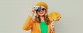 Autumn portrait happy smiling young woman with film camera and yellow maple leaves wearing a french beret on gray background