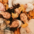 Autumn portrait. Happy young women students playing with leaves, smiling while lying on ground in park, top view Royalty Free Stock Photo