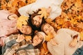 Autumn portrait of Happy four young women students playing with leaves, smiling while lying on ground in park, top view Royalty Free Stock Photo