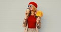 Autumn portrait of smiling young woman with yellow maple leaves and cup of coffee wearing red french beret over gray Royalty Free Stock Photo
