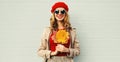 Autumn portrait of smiling young woman with yellow maple leaves wearing red french beret over gray Royalty Free Stock Photo