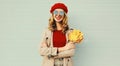 Autumn portrait of smiling young woman with yellow maple leaves wearing red french beret over gray Royalty Free Stock Photo