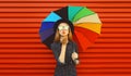 Autumn portrait of stylish young woman posing with colorful umbrella wearing black round hat blowing her lips sends kiss on red Royalty Free Stock Photo