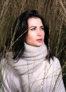 Autumn portrait in the tall grass. Beautiful young woman in sweater and scarf