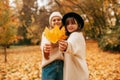 Autumn portrait. Two young women, blurred in background, hold yellow maple leaves in their hands and hold them out to Royalty Free Stock Photo