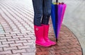 Autumn. Protection in the rain. Woman (girl) wearing pink rubber boots and has umbrella.