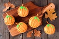 Autumn pumpkin cupcakes on a wooden serving platter over rustic wood