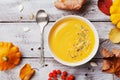 Autumn pumpkin soup decorated seeds and thyme in white bowl on rustic wooden table top view. Cozy lifestyle shot for halloween.