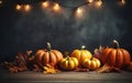 Autumn pumpkins background with copy space, garland with light bulbs, dark bokeh lights, maple leaves. Wooden table. Royalty Free Stock Photo
